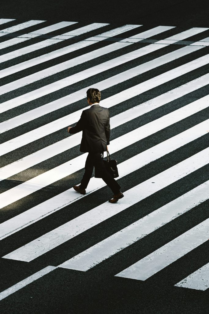 A person in a suit crossing a zebra crossing, seen from above